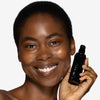 Model holding and showcasing a deep shade of tinted moisturizer