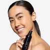 Model holding and showcasing a light shade of tinted moisturizer
