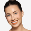 Model showcasing a orangish shade of lip gloss