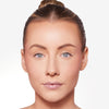 A model with glowing skin and natural makeup, showcasing clear complexion and subtle lip gloss, under soft lighting.