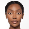 Woman with smooth, radiant skin and natural makeup, featuring glossy lips and subtle eye enhancement.