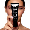 A person holds a sleek black tube labeled "OFIR," displaying a size of 1 FL OZ / 30 ML, with a focus on the product.