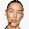 Model holding a lip liner to her mouth, showcasing a pink/nude shade