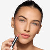 Model holding and showcasing a light pink lipstick