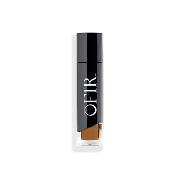 A sleek, black cosmetic bottle labeled "OFIR" with a transparent section showcasing a warm beige product inside.