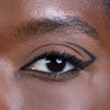 Close-up of an eye with dramatic black eyeliner and neatly groomed eyebrow, highlighting makeup application.