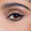 Close-up of an eye with expertly applied winged eyeliner and well-defined brows, showcasing a natural makeup look.