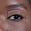 Close-up of a person's eye with a defined eyebrow and purple eyeliner outlining the upper eyebrow shape, showcasing makeup precision.