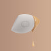 A white makeup sponge with a soft texture is angled to show liquid foundation dripping from its edge against a beige background.