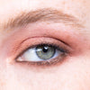 Close-up of an eye with shimmering rose gold eyeshadow, illustrating a subtle and elegant makeup look.