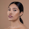 A person with smooth, natural makeup and glossy lips, showcasing a sophisticated makeup look against a neutral background.