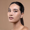 A person with smooth, glowing skin and natural makeup, set against a neutral background, showcasing a fresh and polished look.