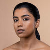 A woman with smooth, glowing skin and natural makeup showcases elegant beauty against a neutral background.