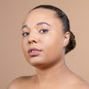 A close-up of a woman with smooth, glowing skin and natural makeup, set against a neutral background.