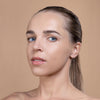 A woman with smooth, clear skin and light makeup, showcasing a natural look with a neutral background.