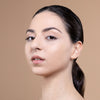 A close-up of a person with smooth, radiant skin, showcasing subtle makeup on the eyes and natural lip color against a neutral background.