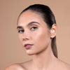 A model with flawless, glowing skin and sleek hair pulled back, showcasing a minimalist makeup look on a neutral background.