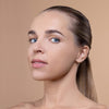A person with smooth, radiant skin and sleek hair is shown against a neutral background, highlighting the application of beauty products.