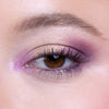 Close-up of an eye with expertly applied pink and purple eyeshadow, accentuating browns and highlighting lashes.