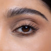 Close-up of a well-groomed eyebrow and eye with natural makeup and defined lashes, showcasing a beauty product's effect.