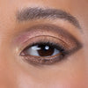 Close-up of an eye featuring shimmery metallic eyeshadow in gold and bronze shades, accentuated with a hint of pink, perfect for creating a glamorous look.
