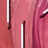 Close-up of three lip gloss applicator wands resting on swatches of glossy lip color in varying shades of pink 
