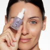 Model holding a dropper bottle of OFIR serum, showcasing clear and radiant skin.