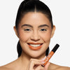 Model holding a  lip gloss showcasing a orangish lip color
