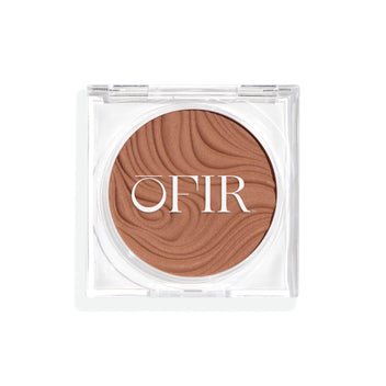 Compact cream bronzer in a light nude shade with a shiny finish in a transparent case