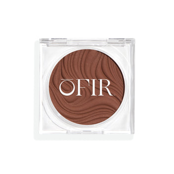 Compact cream bronzer in a medium-dark nude shade with a shiny finish in a transparent case