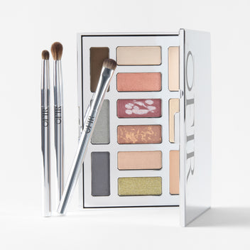 Makeup palette featuring a variety of eyeshadow shades in warm and cool tones, accompanied by three application brushes.