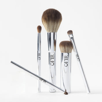 Five OFIR makeup brushes with chrome handles arranged upright on white background