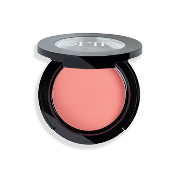 Round compact of peach-colored blush in a sleek black case with a clear lid displaying the brand logo.