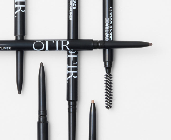 Assorted OFIR eyebrow pencils and liners in black packaging with spoolie brush and pencil tips visible