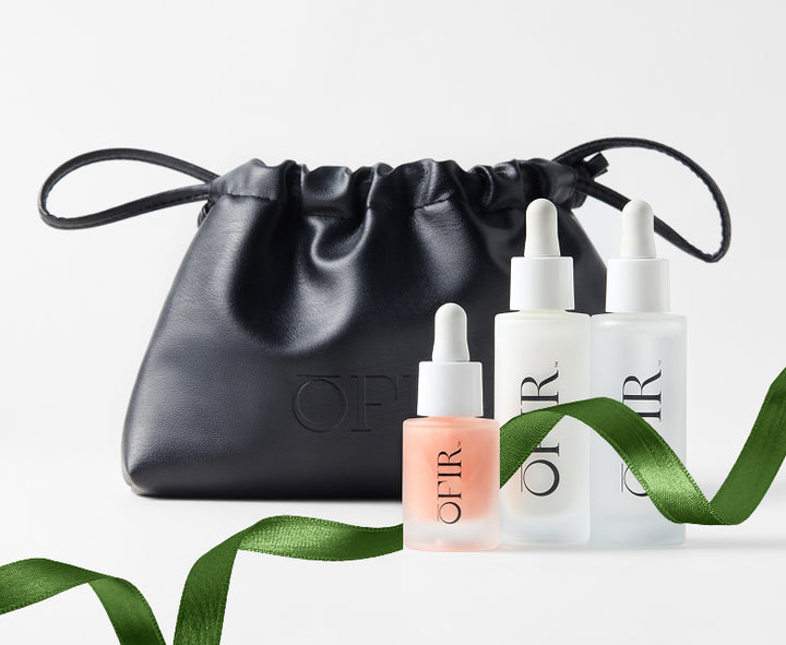 black cosmetic bag with three OFIR skincare dropper bottles and green ribbon accent
