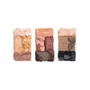 Triple palette of crushed eyeshadows in neutral and earthy tones, including soft pink, golden, copper, brown, and charcoal shades, arranged in a vertical format.