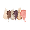 six swatches of crushed eyeshadow in shades of cream, brown, bronze, purple, gold, and coral, arranged vertically on a white background.