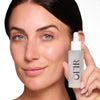 Woman holding a dropper bottle labeled "OFIR," showcasing smooth and radiant skin.