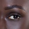 Close-up of a person's eye showcasing perfectly groomed eyebrows and smooth, radiant skin, highlighting beauty and skincare products.