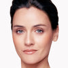 Woman with flawless complexion, subtle eye makeup, and natural lip color, showcasing a polished and refined look.