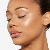 A woman with smooth, radiant skin and subtle makeup, highlighting a luminous complexion and naturally glossy lips.