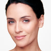 Close-up of a woman with clear skin and subtle makeup, featuring neutral eyeshadow and glossy lips.