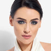 Close-up of a woman with elegant makeup featuring bold, smoky eyes and nude lips, complemented by a smooth, flawless complexion.