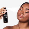Model with dewy glowing skin holding and spraying OFIR Ever Set setting spray