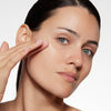 Woman applying skincare product to her cheek, showcasing smooth complexion and highlighting the product's moisturizing effect.