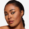 Model showcasing a gold and brown eye pigmentation in a radiant makeup look.