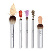 A set of five silver makeup brushes with different heads, accompanied by powder and cream samples in various colors.