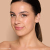 A woman with a natural makeup look showcases glowing skin and subtle lip color against a neutral backdrop, emphasizing the beauty products available.
