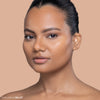 Person with smooth, glowing skin wearing a subtle, natural makeup look against a beige background.
