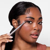 A person applies eye makeup using a blending brush, showcasing expertly blended eyeshadow and polished makeup.